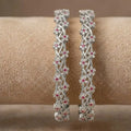 Silver-plated bangle featuring two zirconia-encrusted clover motifs on a jewelry display.
