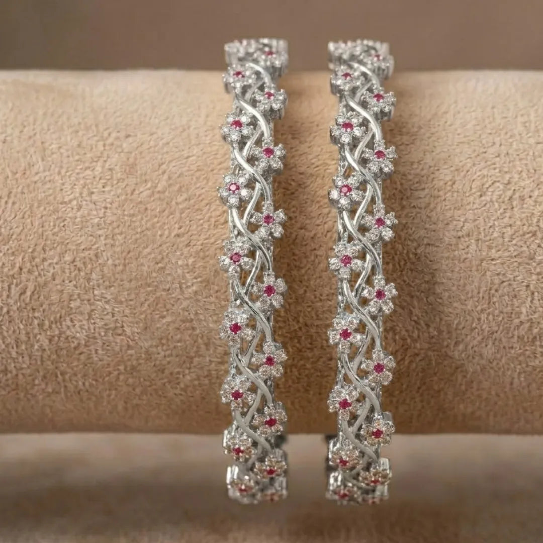 Silver-plated bangle featuring two zirconia-encrusted clover motifs on a jewelry display.