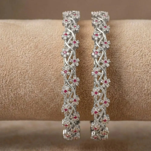 Silver-plated bangle featuring two zirconia-encrusted clover motifs on a jewelry display.
