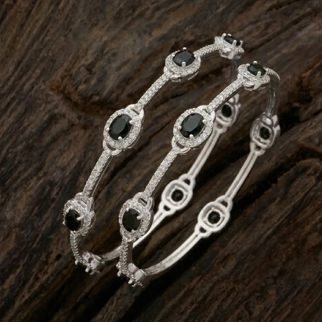 Silver-plated eternity bangle with pavé-set zirconia stones displayed on a black surface.