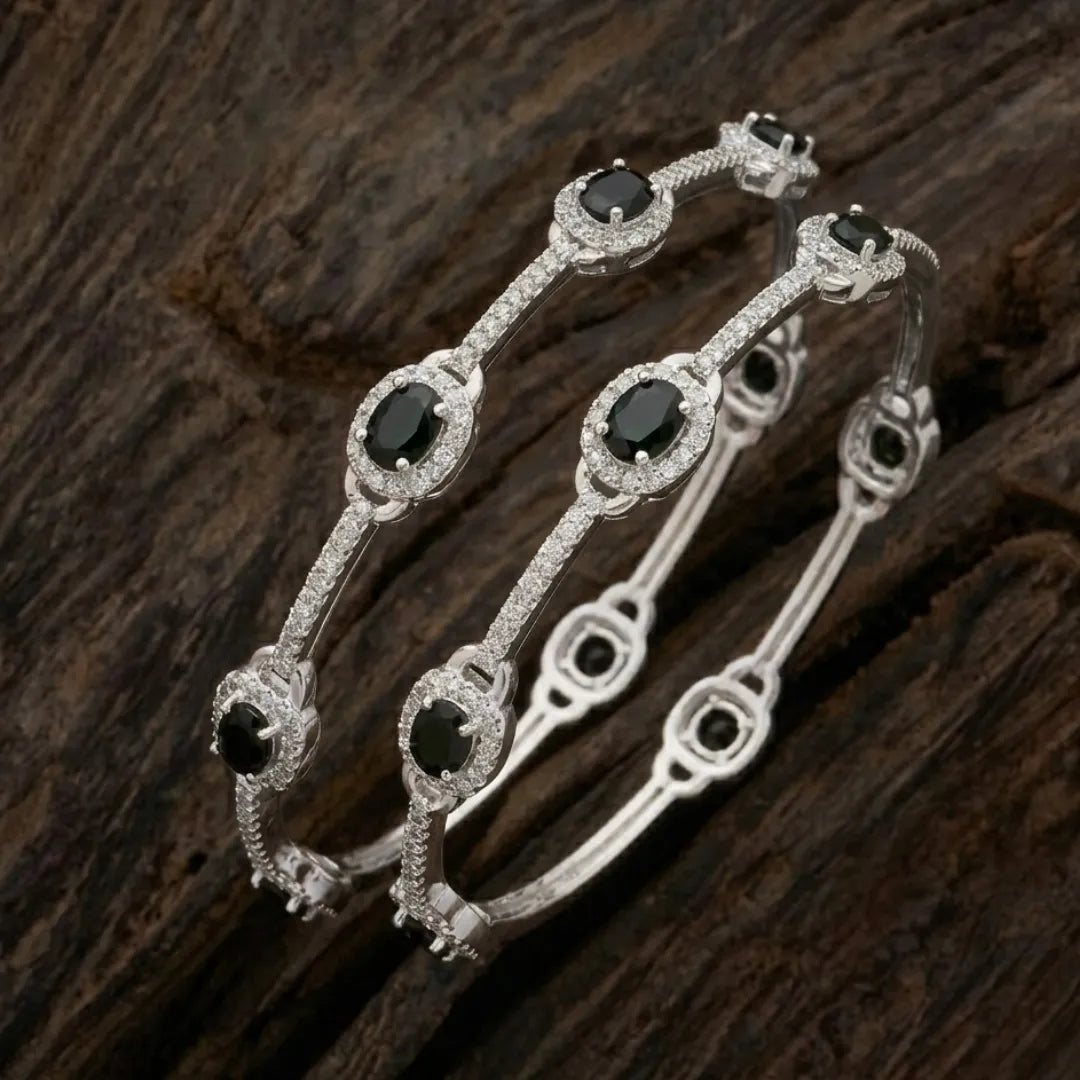 Silver-plated eternity bangle with pavé-set zirconia stones displayed on a black surface.