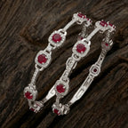 Silver-plated eternity bangle with red gemstones and white zirconia floral design.