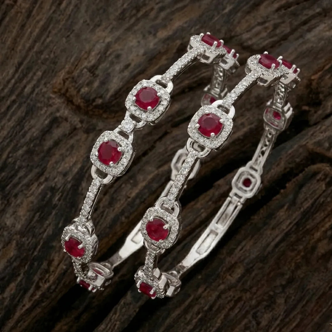 Silver-plated eternity bangle with red gemstones and white zirconia floral design.