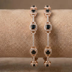 Elegant golden floral bangle featuring midnight black gemstones on a professional display.