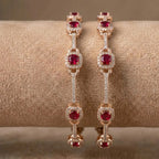 Gold-plated eternity bangle with red center stones and white floral zirconia design.