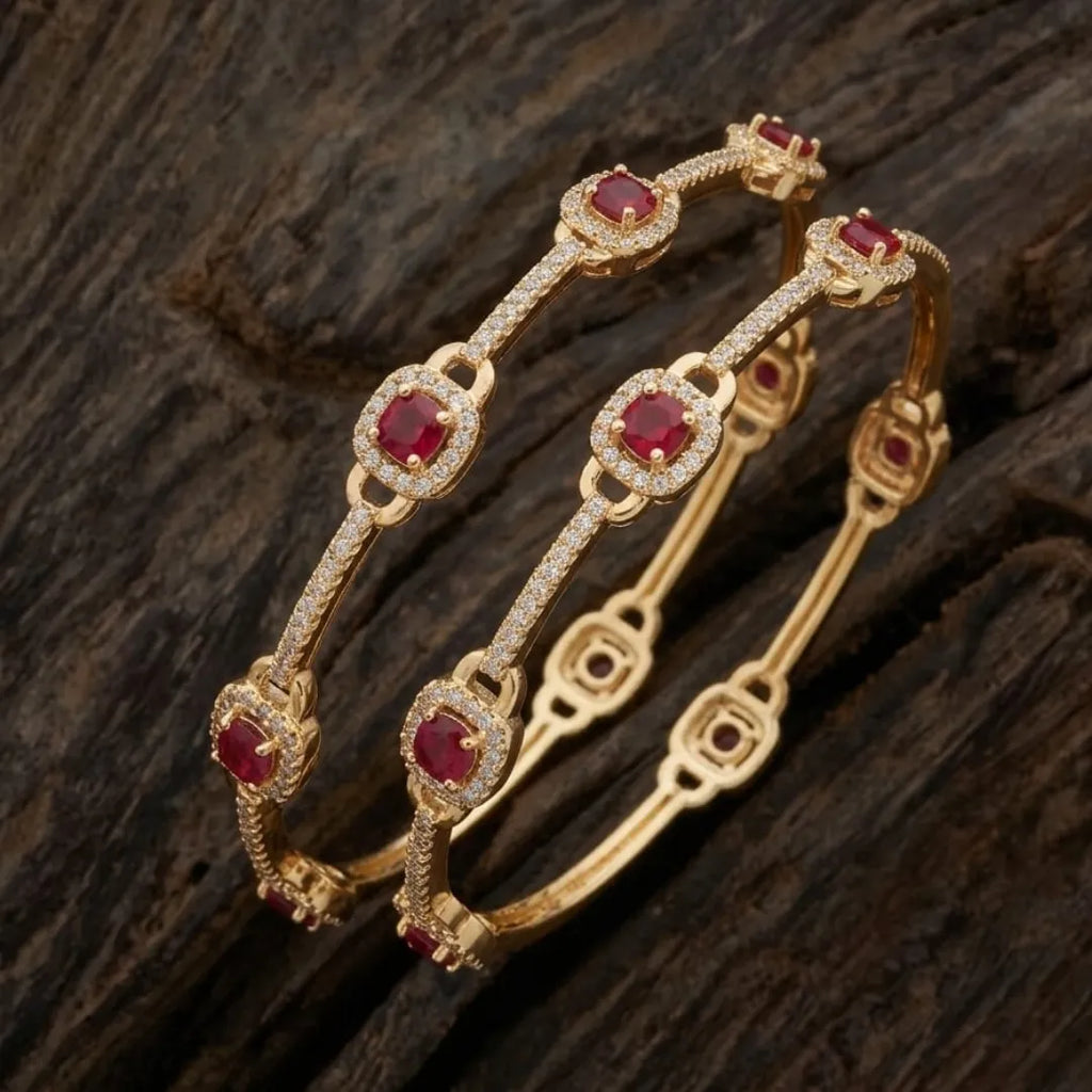 Gold-plated eternity bangle with red center stones and white floral zirconia design.