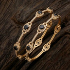 Elegant golden floral bangle featuring midnight black gemstones on a professional display.