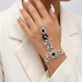 Elegant woman wearing a black and silver floral zirconia hand chain with a white formal blazer.