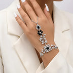 Elegant woman wearing a black and silver floral zirconia hand chain with a white formal blazer.