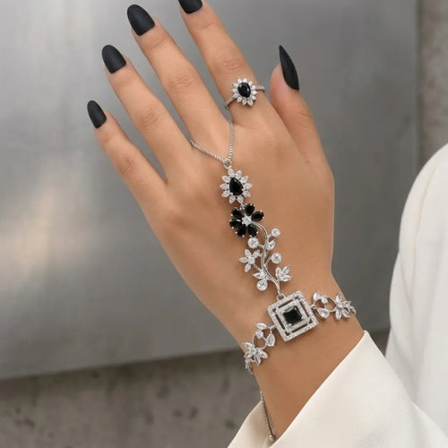 Elegant woman wearing a black and silver floral zirconia hand chain with a white formal blazer.
