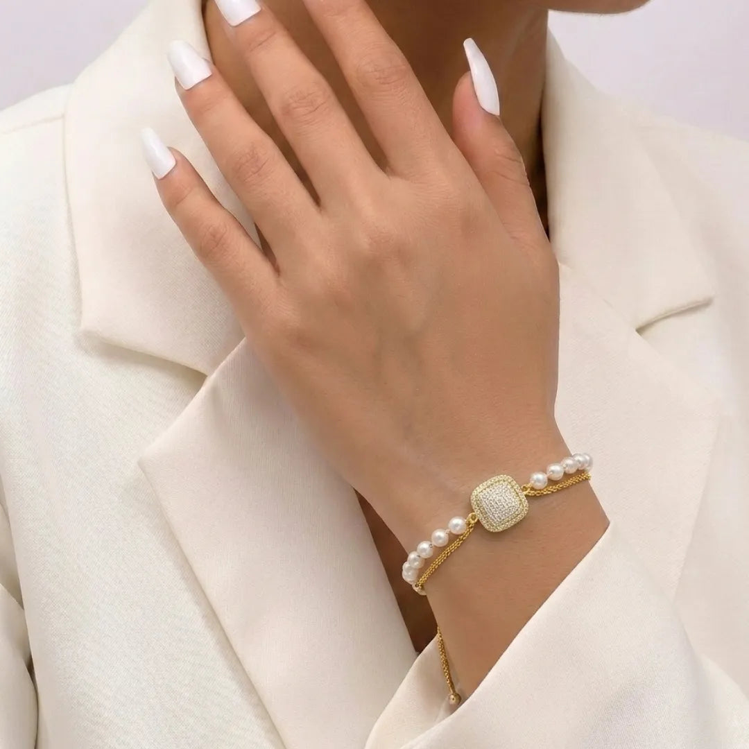 Golden cushion-cut zirconia layered bracelet featuring white pearls on a professional display stand.