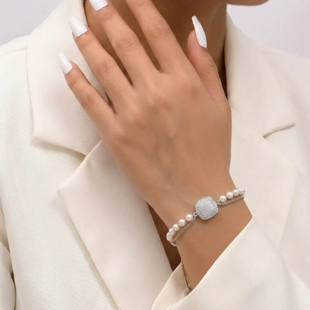 Silver-plated cushion zirconia bracelet with double-layer pearl and chain design on a jewelry display.