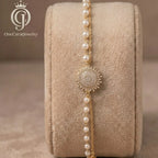 Woman wearing a delicate sunburst pearl bracelet with a white blazer for a luxury look.
