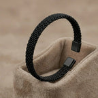 Silver-toned stainless steel cuff bracelet with three parallel grooved lines on a professional stand.
