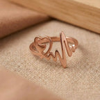 Rose gold ring with heart and heartbeat design on a beige fabric background