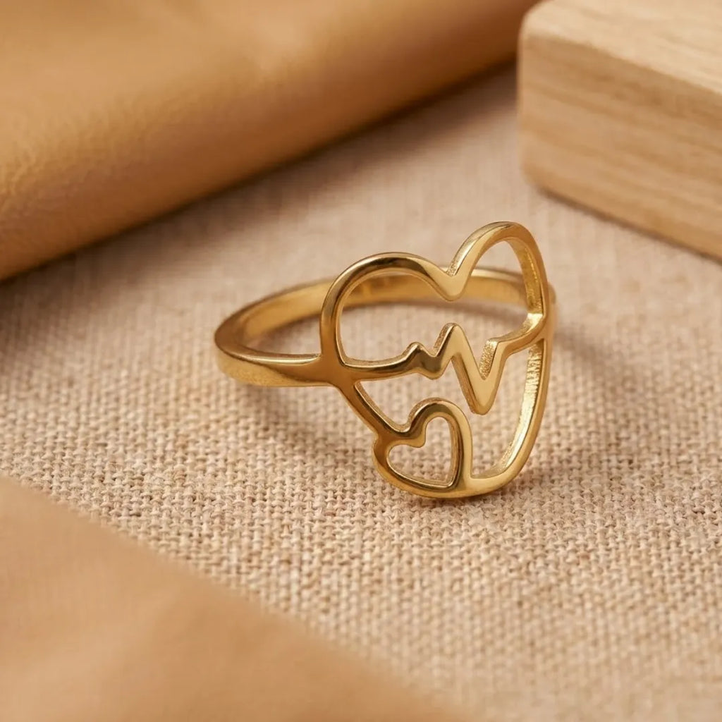 Gold ring with heart design on a beige fabric background