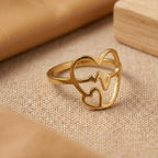 Gold ring with heart design on a beige fabric background
