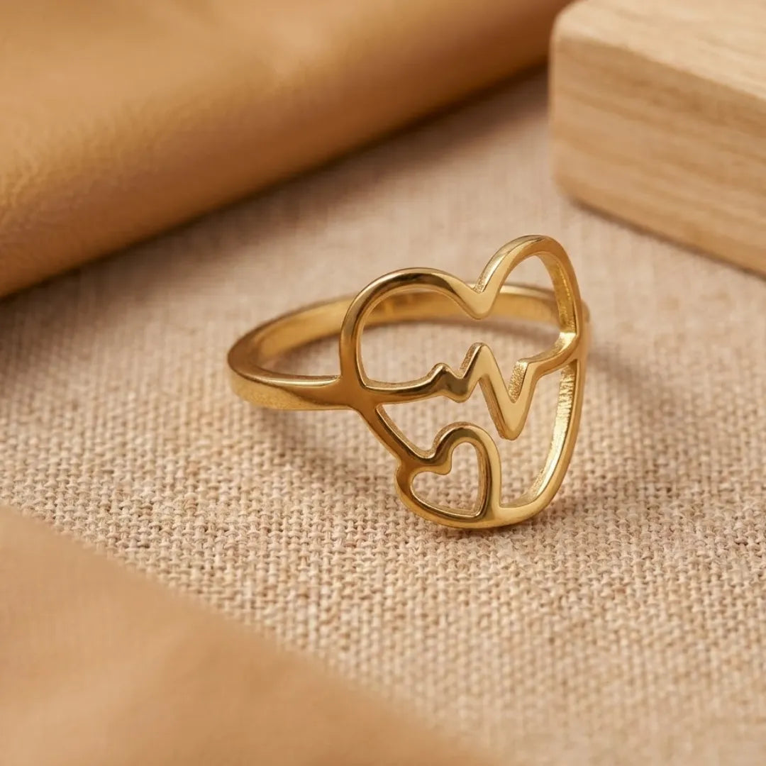 Gold ring with heart design on a beige fabric background