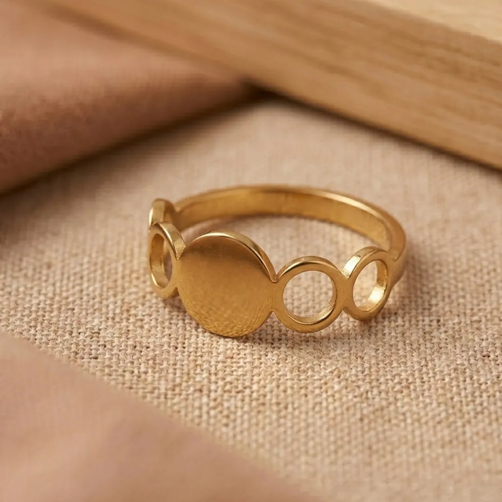 Gold ring with circular design on a beige fabric background