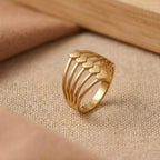 Gold ring with heart designs on a beige fabric background