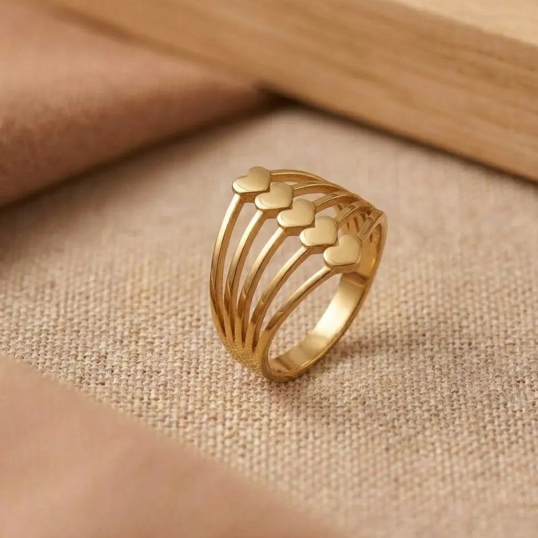 Gold ring with heart designs on a beige fabric background