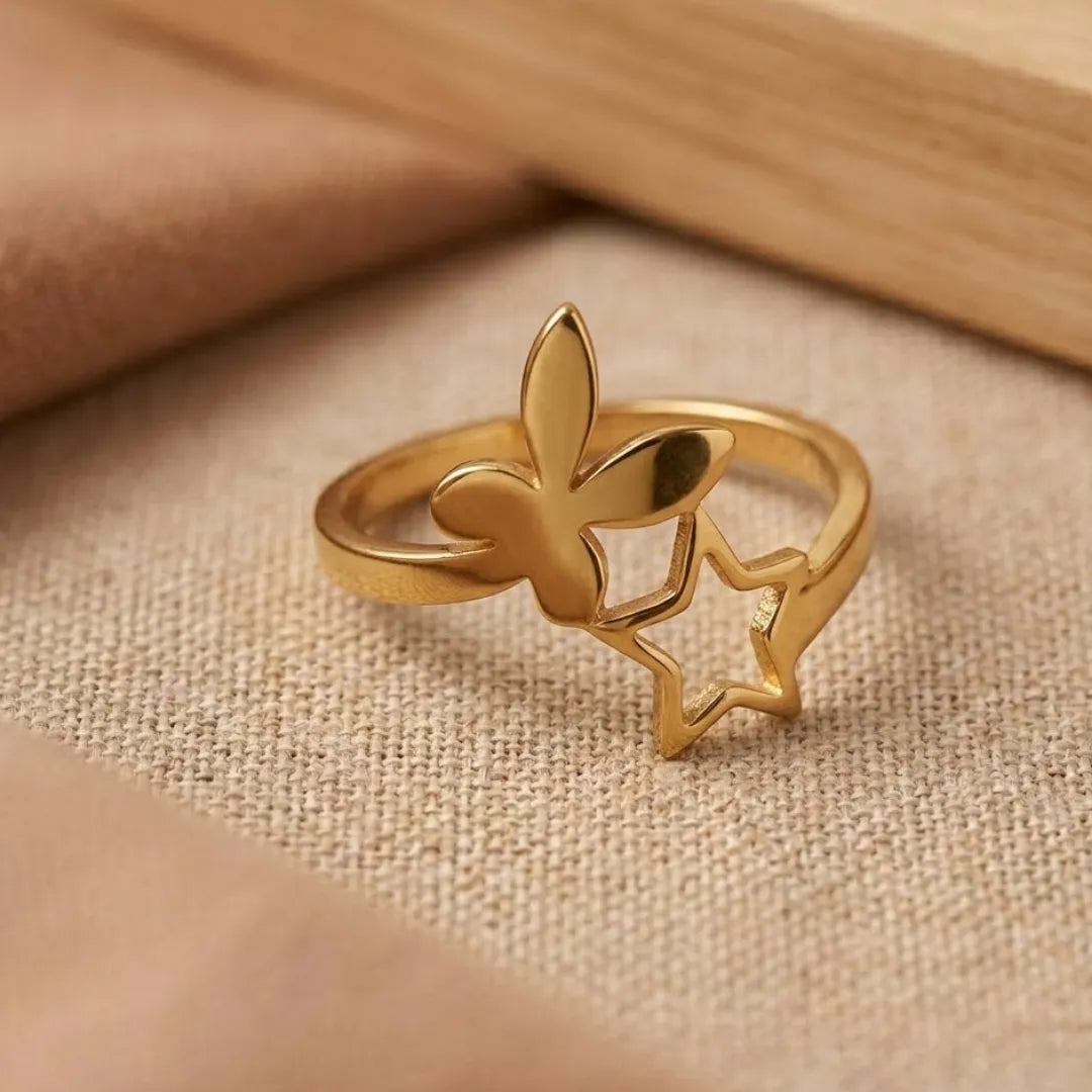 Gold ring with butterfly design on a beige fabric background