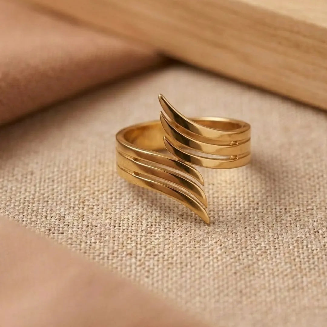 Gold ring with wavy design on a beige fabric background