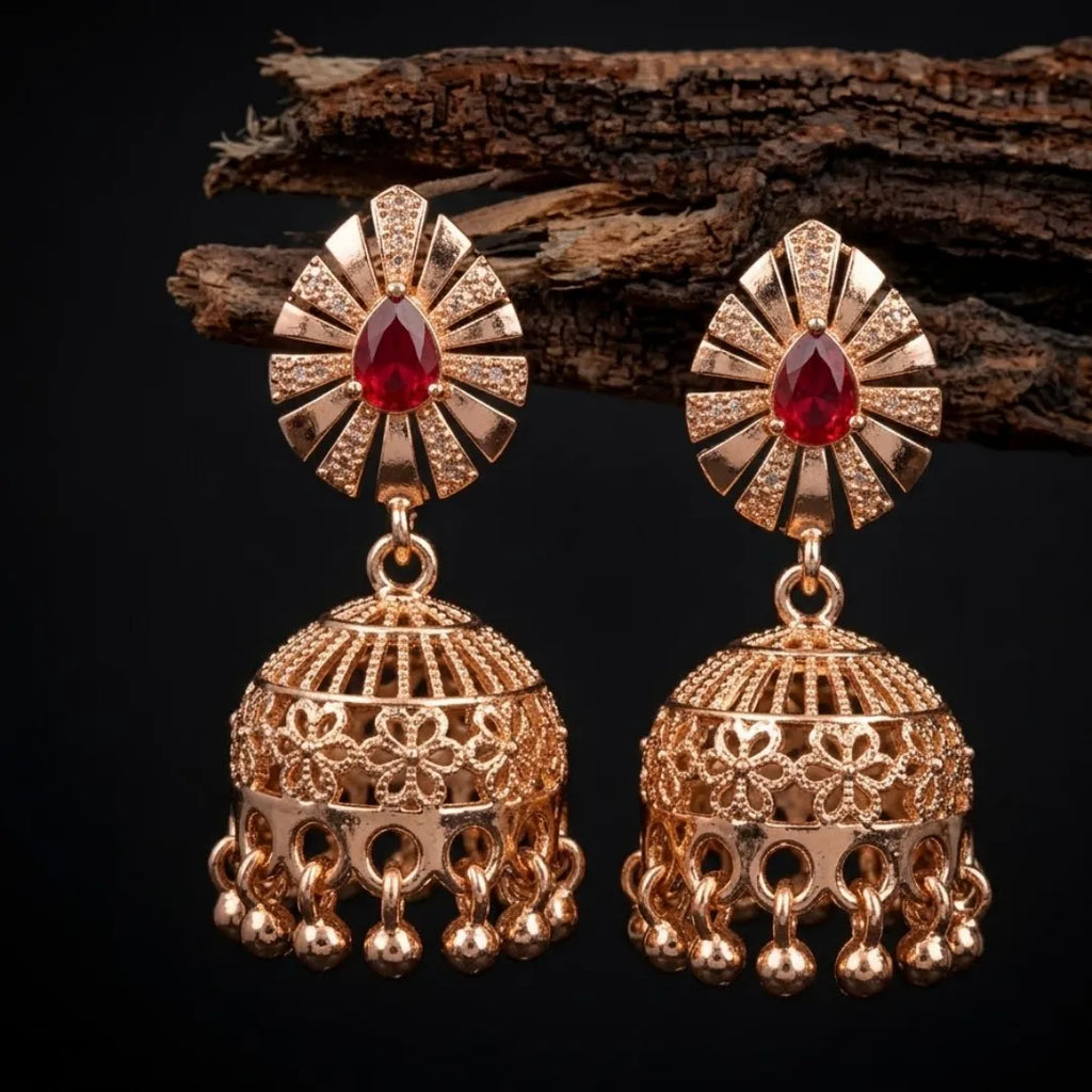 Gold earrings with red gemstones on a dark background