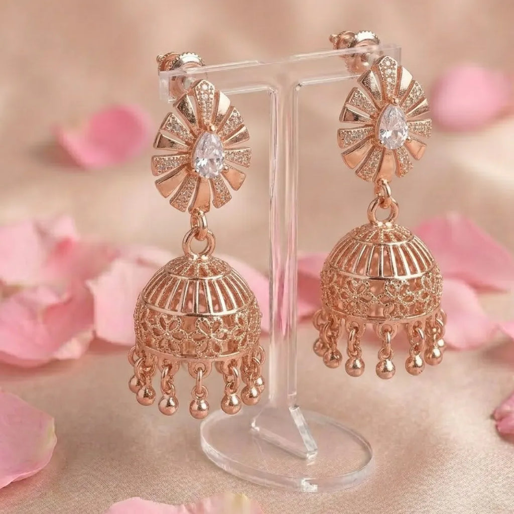 Rose gold earrings on a stand with pink floral background