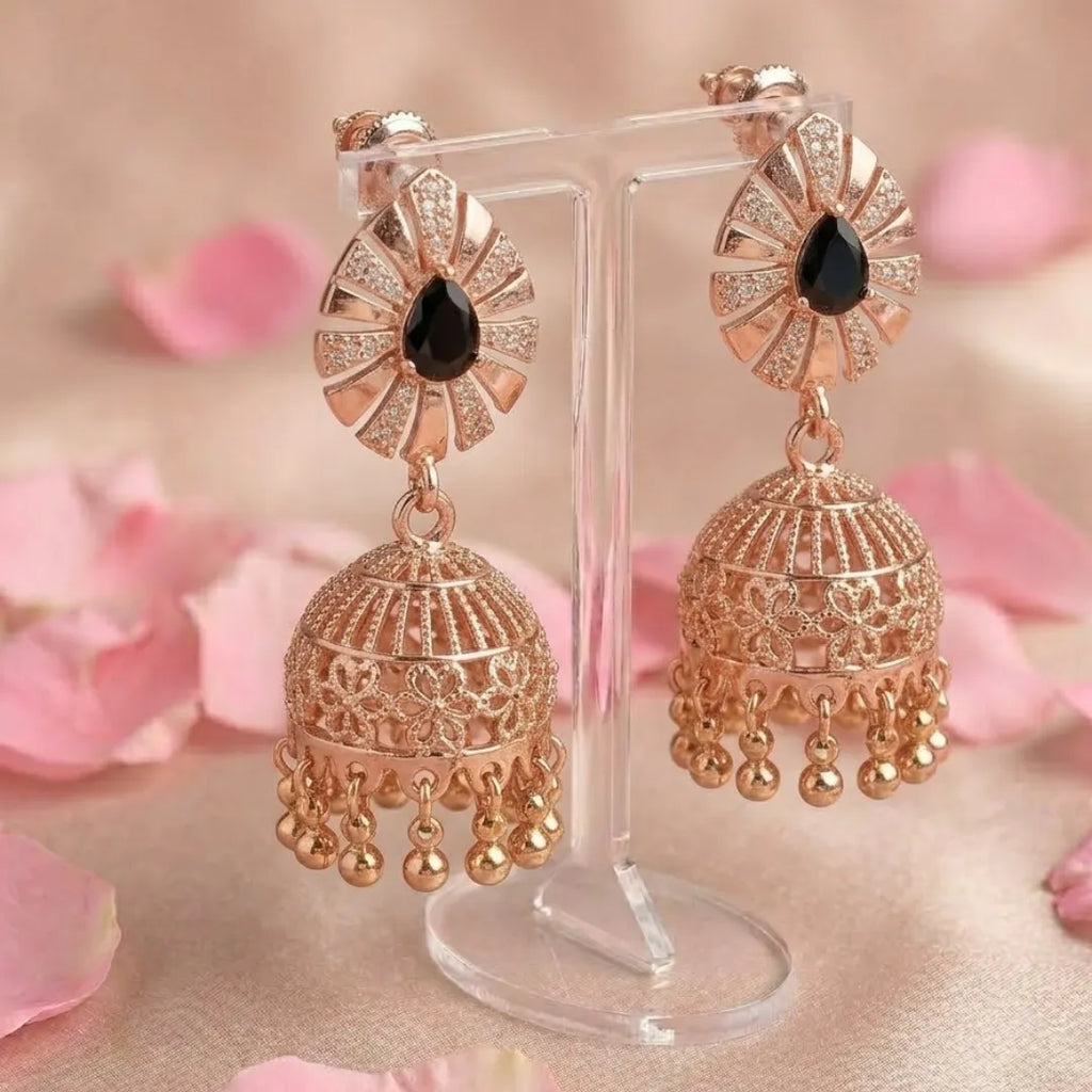 Rose gold earrings with black gemstones on a stand with pink floral background
