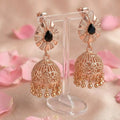 Rose gold earrings with black gemstones on a stand with pink floral background