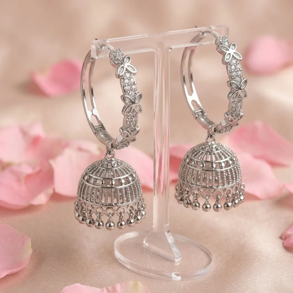 Silver hoop earrings on a stand with pink floral background