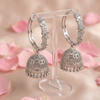 Silver hoop earrings on a stand with pink floral background