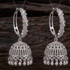Pair of silver hoop earrings with intricate designs on a wooden background