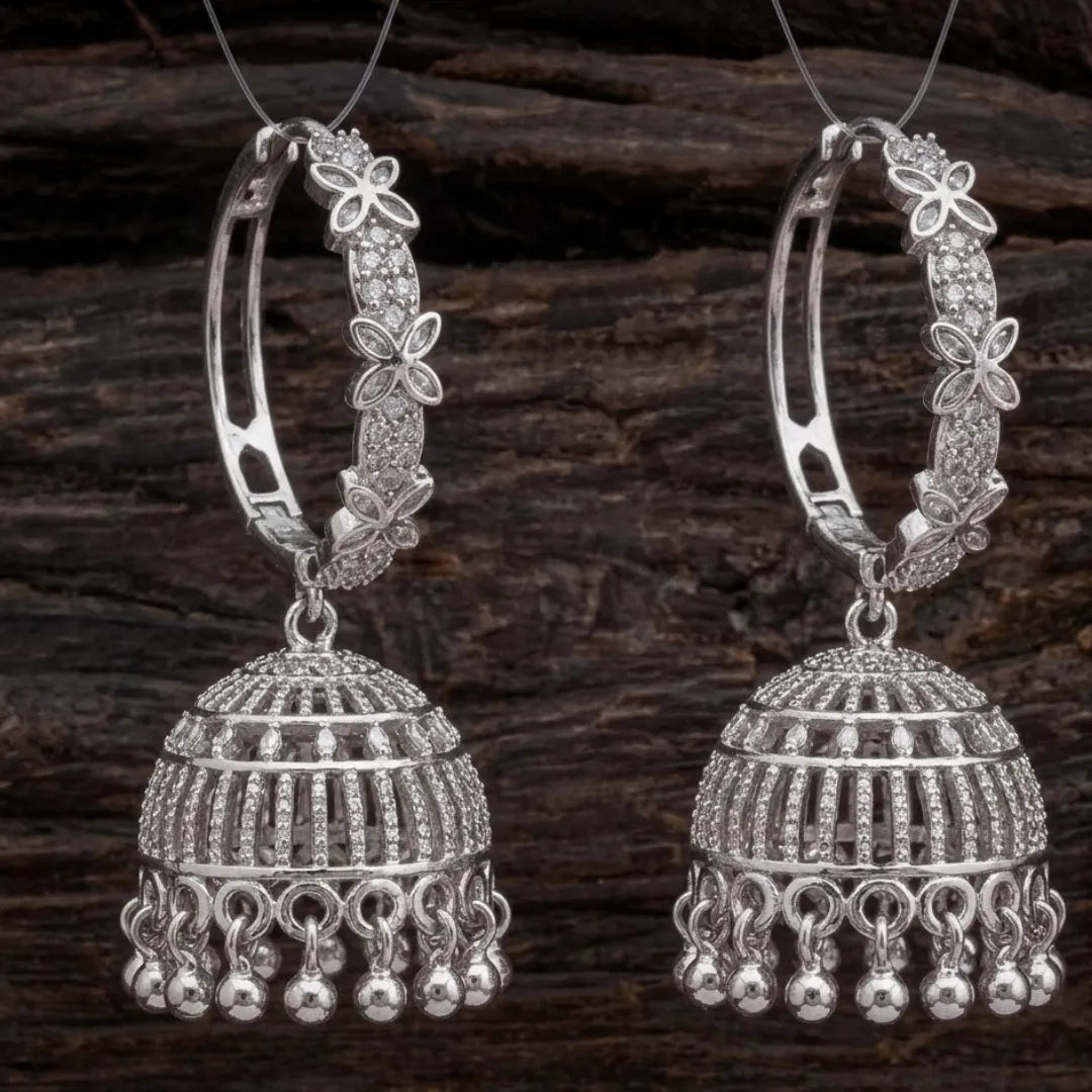 Pair of silver hoop earrings with intricate designs on a wooden background