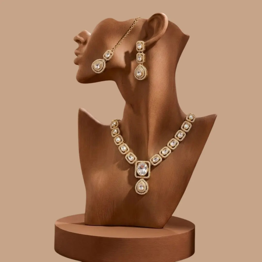 Royal gold-plated necklace set with large crystals and maang tikka on a black reflective surface.