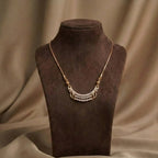 Gold necklace with pearls on a brown mannequin bust against a brown fabric background