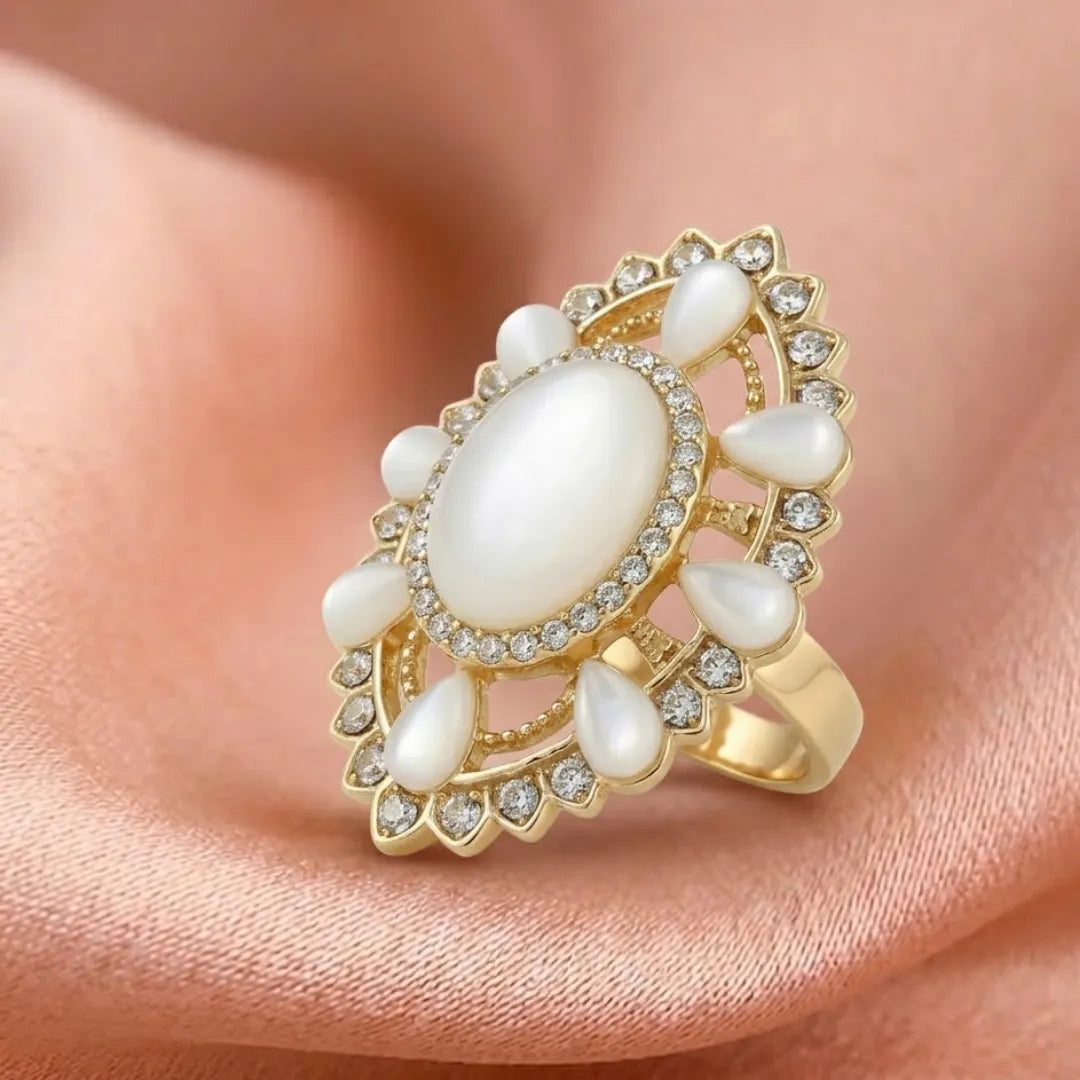 Gold ring with pearls and gemstones on a soft pink background