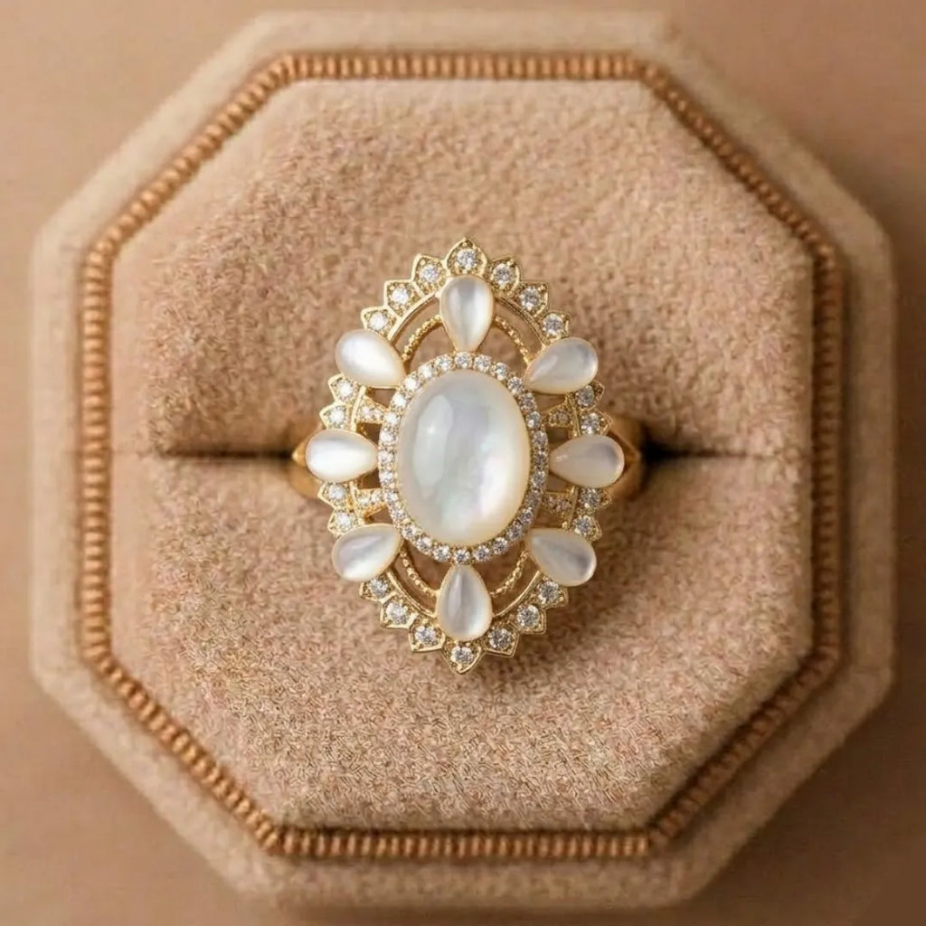 Gold ring with a large central stone and smaller stones on a beige cushion