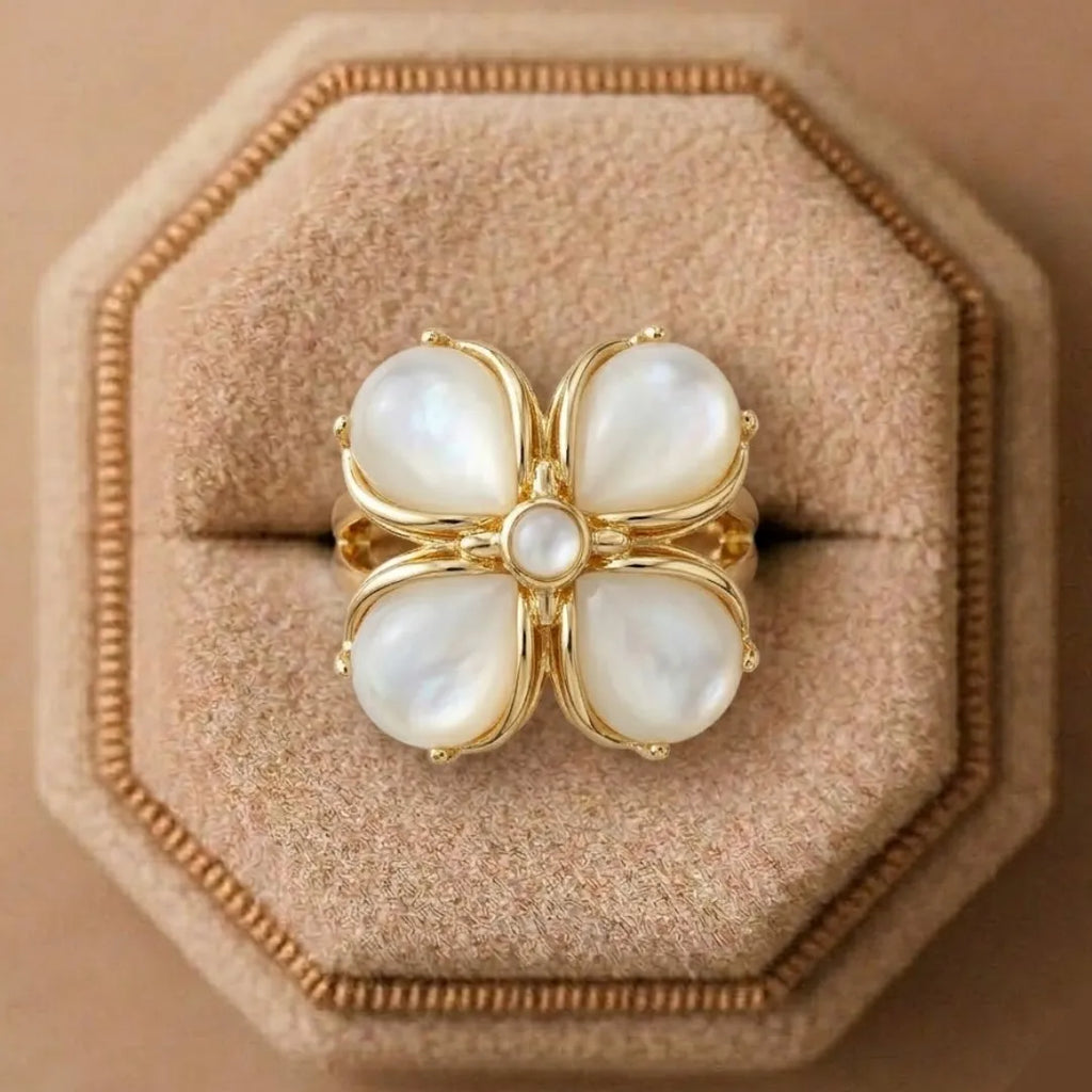 Gold ring with pearl-like stones on a beige cushion