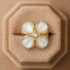 Gold ring with pearl-like stones on a beige cushion
