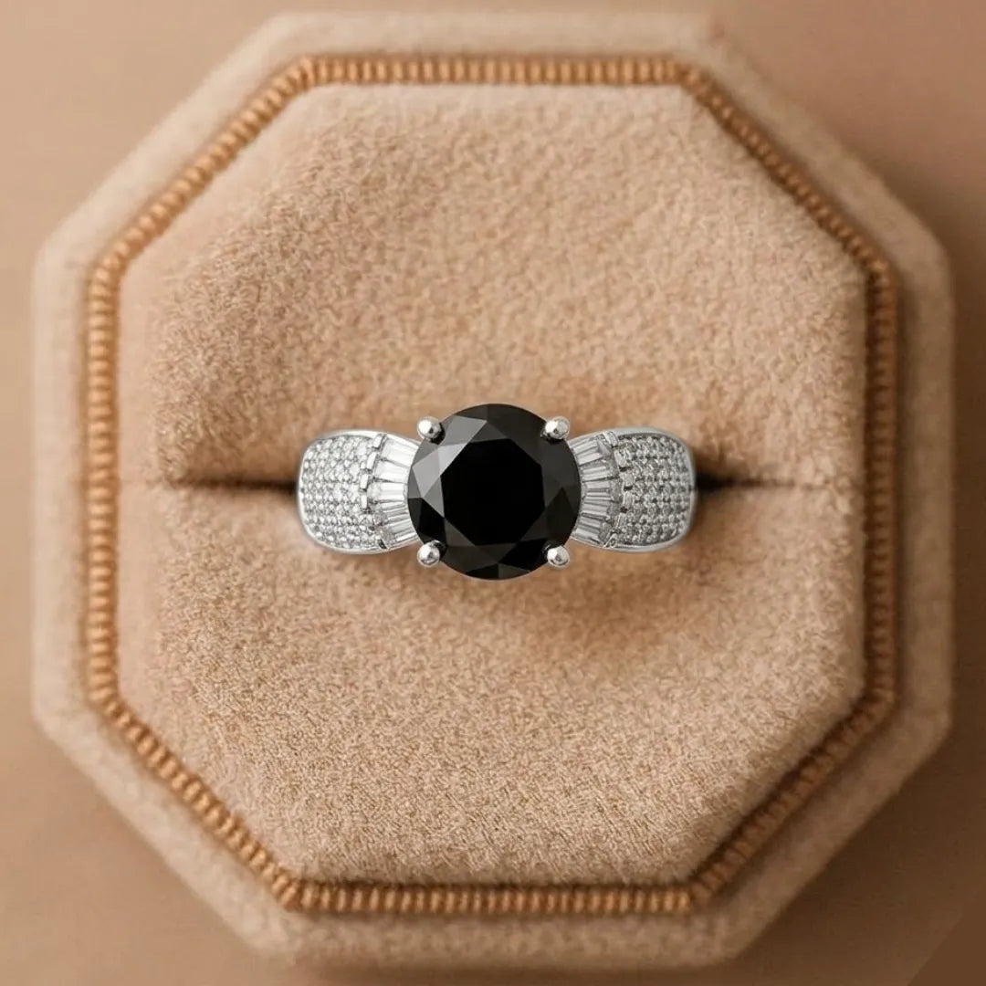 Ring with a black gemstone and diamond accents on a beige cushion