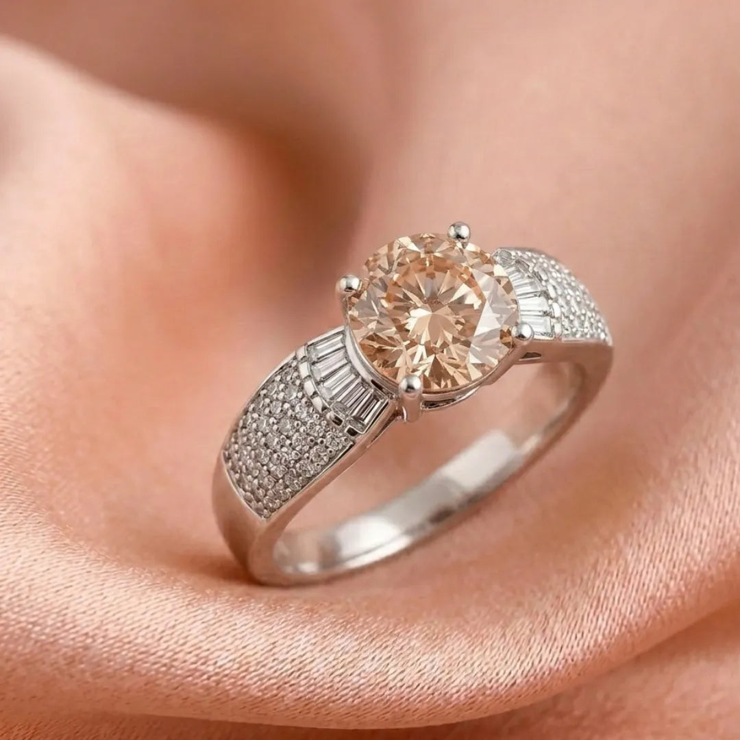 Diamond ring with a peach-colored center stone on a soft pink background