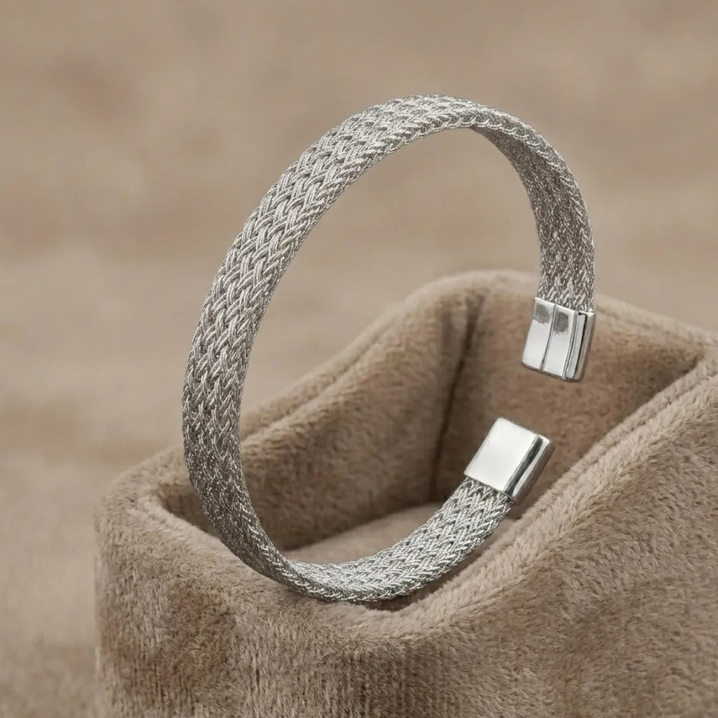 High-polish silver V-shape geometric cuff bracelet on a minimalist display stand.