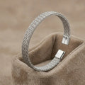 High-polish silver V-shape geometric cuff bracelet on a minimalist display stand.