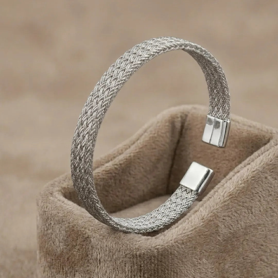 High-polish silver V-shape geometric cuff bracelet on a minimalist display stand.