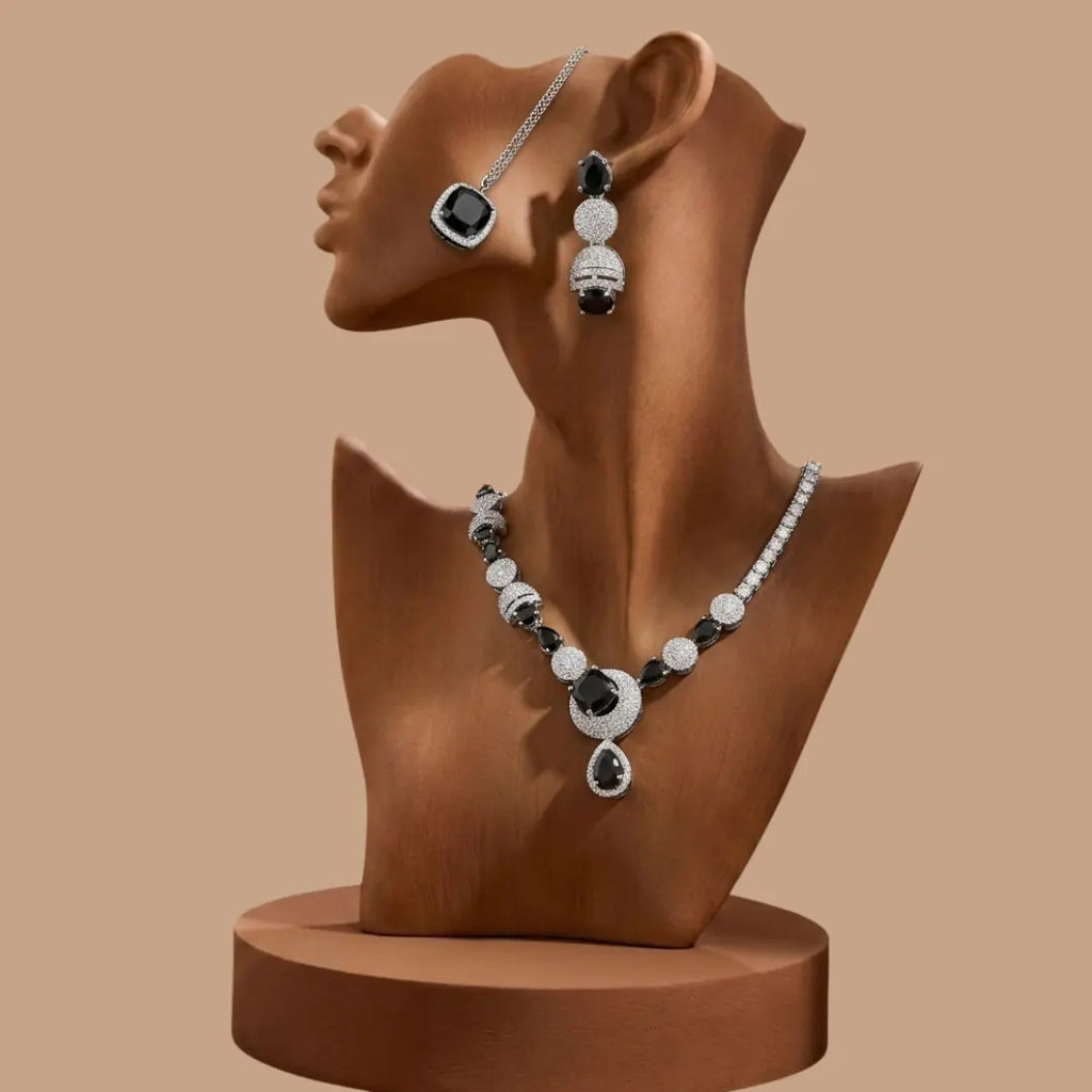 Luxury black and silver zirconia necklace set with earrings and pendant on a black geometric background.