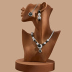 Luxury black and silver zirconia necklace set with earrings and pendant on a black geometric background.